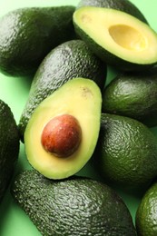 Photo of Whole and cut avocados on green background, above view