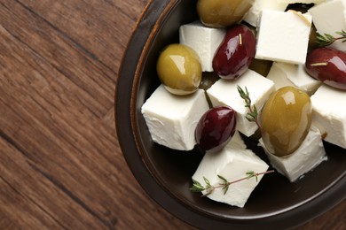 Photo of Marinated olives with feta cheese and rosemary on wooden table, top view. Space for text