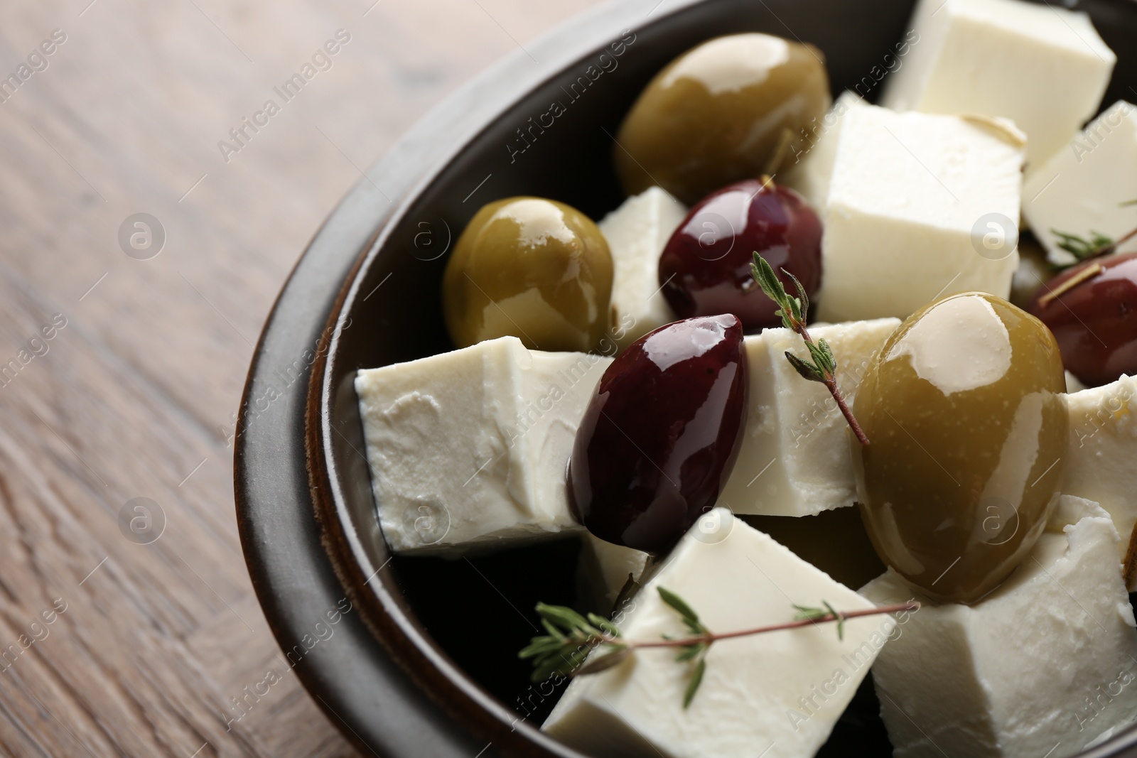 Photo of Marinated olives with feta cheese and rosemary on table, closeup