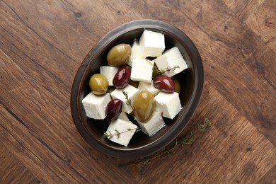 Photo of Marinated olives with feta cheese and rosemary on wooden table, top view