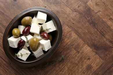 Photo of Marinated olives with feta cheese and rosemary on wooden table, top view. Space for text