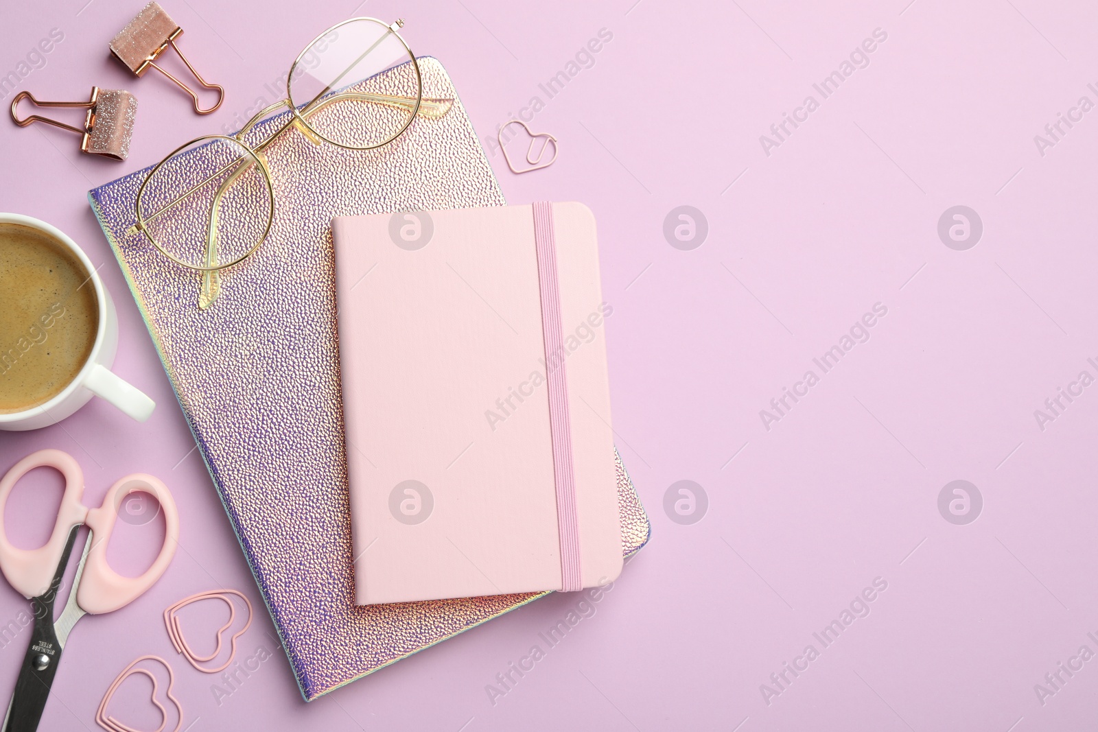 Photo of Paper clips, other different stationery, glasses and coffee on lilac background, flat lay. Space for text