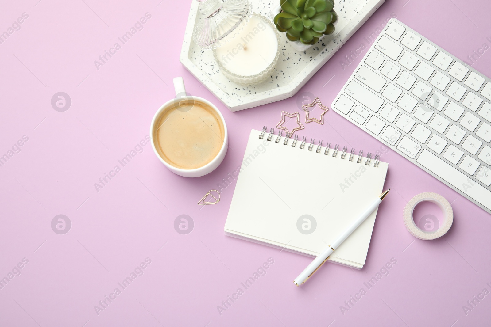 Photo of Paper clips, other different stationery, computer keyboard, coffee and decor on lilac background, flat lay. Space for text