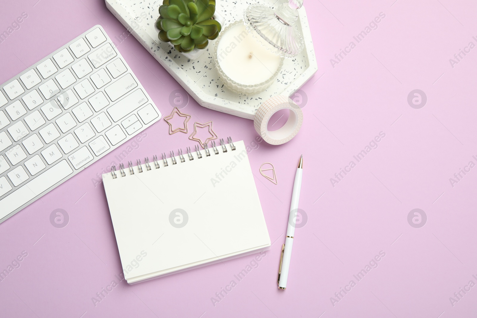 Photo of Paper clips, other different stationery, computer keyboard and decor on lilac background, flat lay. Space for text