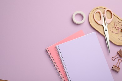 Photo of Paper clips and other different stationery on lilac background, flat lay. Space for text