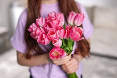 Photo of Teenage girl with bouquet of tulips indoors, closeup