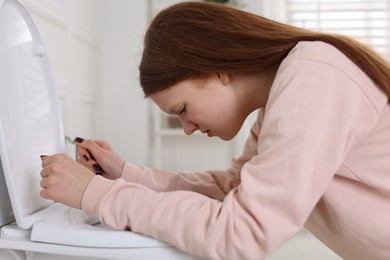 Photo of Teenage girl suffering from nausea over toilet bowl in bathroom. Bulimia