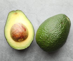 Photo of Whole and cut avocados on light grey table, flat lay