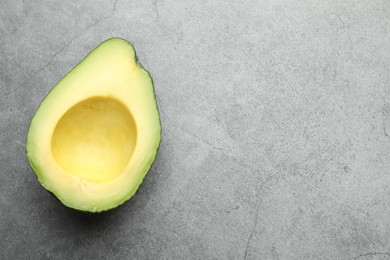 Photo of Half of ripe avocado on light grey table, top view. Space for text