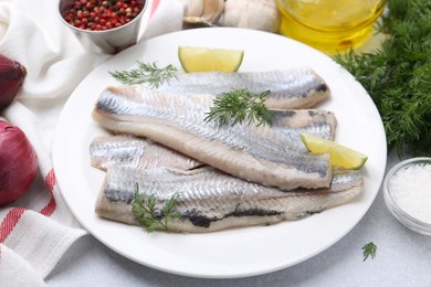 Photo of Marinated herring fillets with lime and dill on grey table, closeup