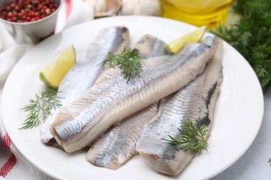 Photo of Marinated herring fillets with lime and dill on grey table, closeup