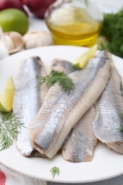 Marinated herring fillets with lime and dill on grey table, closeup