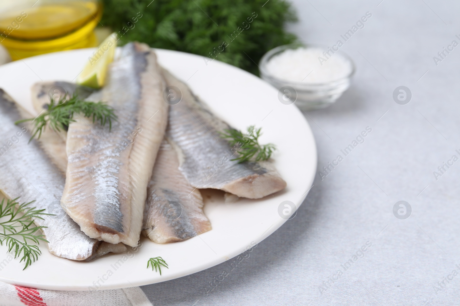 Photo of Marinated herring fillets with dill on grey table, closeup. Space for text