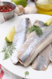 Photo of Marinated herring fillets with lime and dill on table, closeup