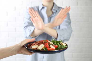 Photo of Woman refusing to eat meal near white brick wall, selective focus. Food allergy concept