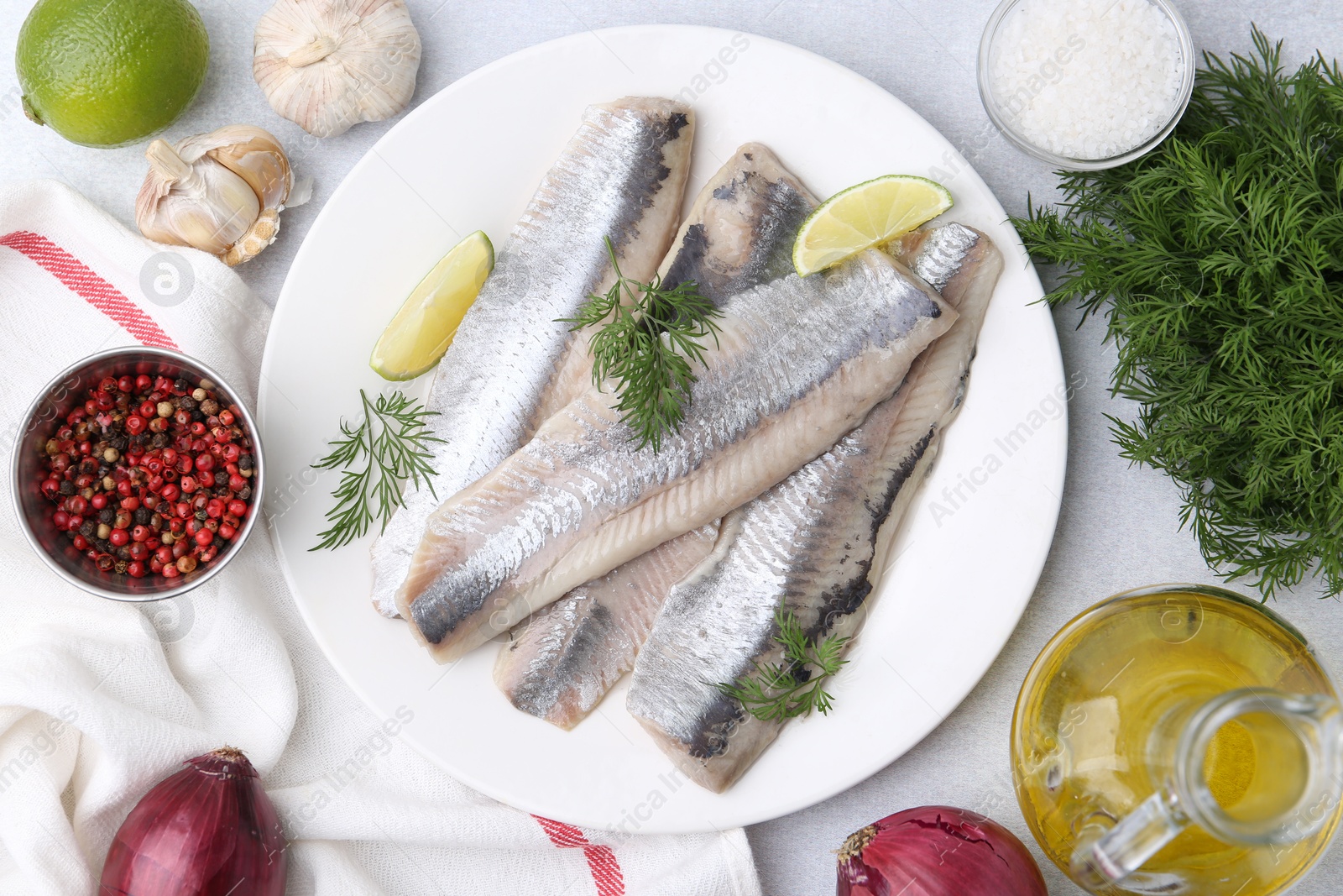 Photo of Marinated herring fillets with lime, dill and other products on grey table, flat lay