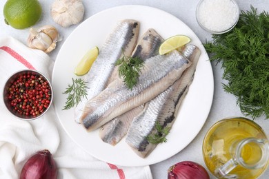 Photo of Marinated herring fillets with lime, dill and other products on grey table, flat lay