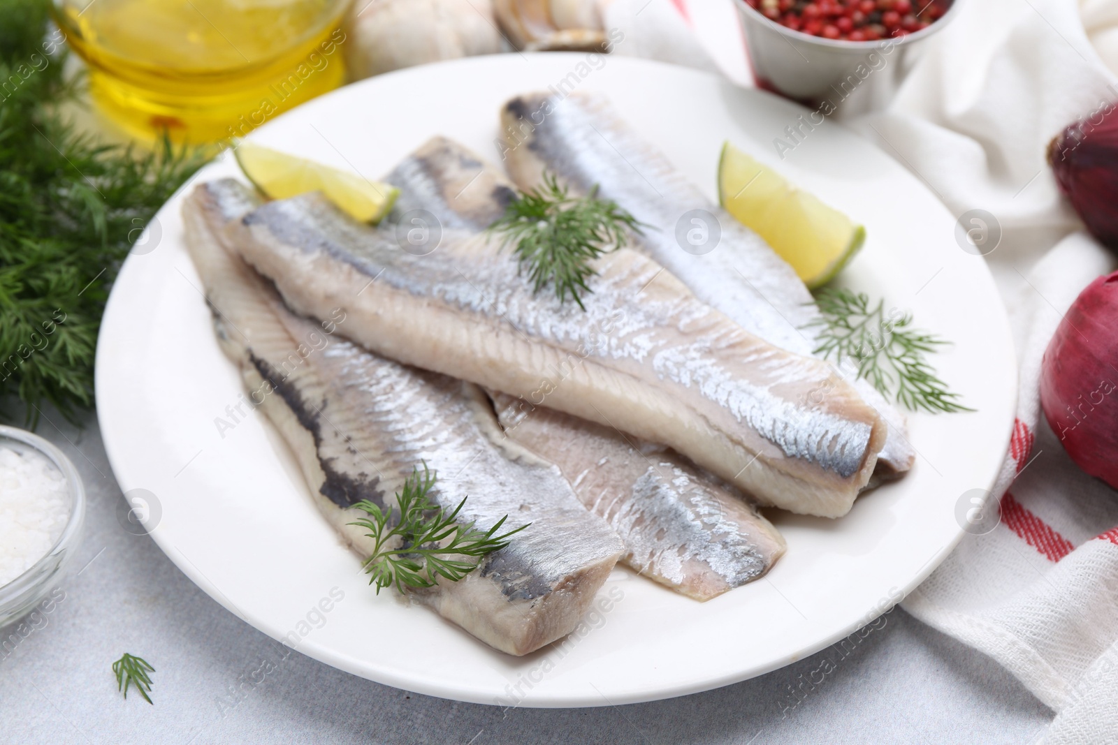 Photo of Marinated herring fillets with lime and dill on grey table, closeup