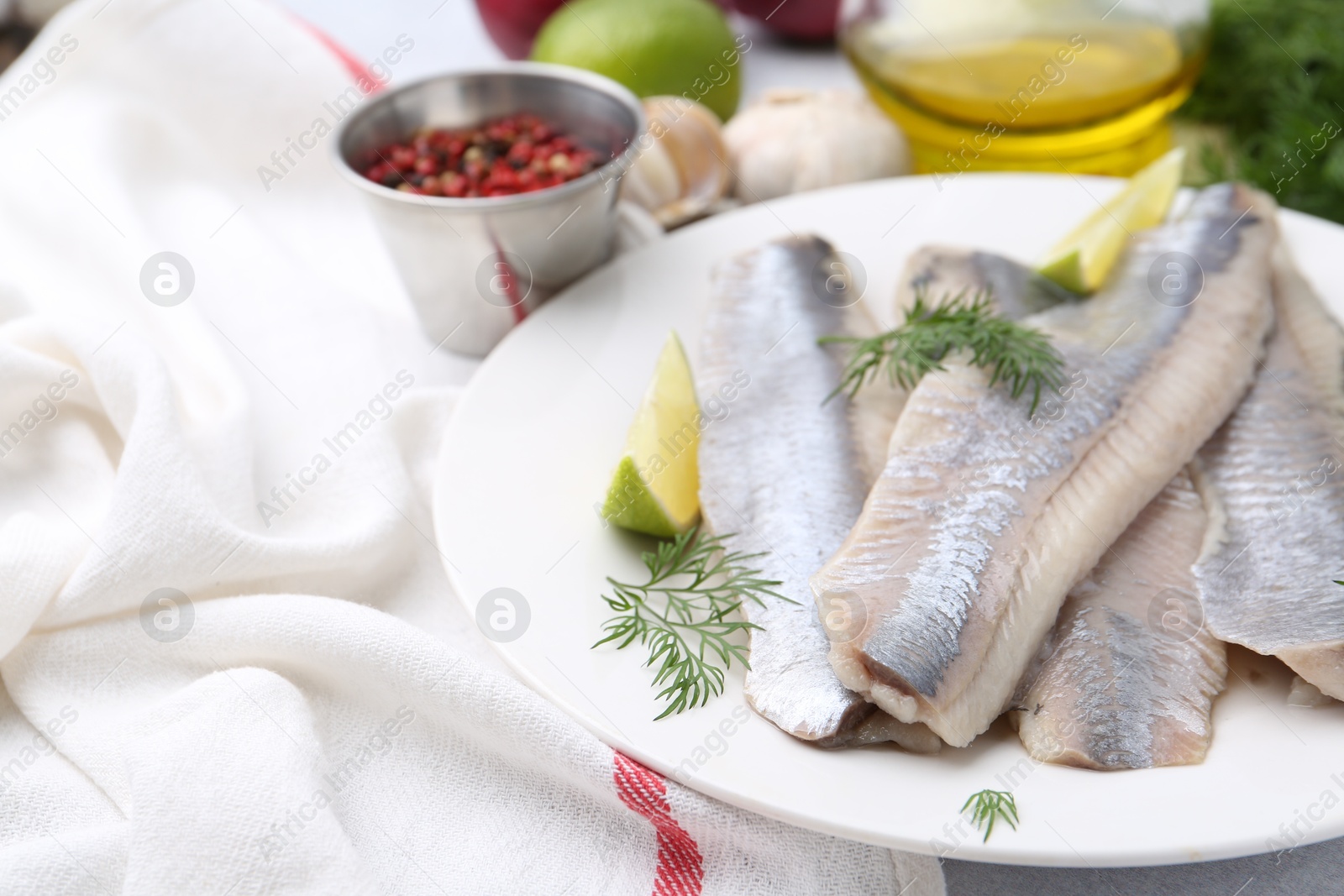 Photo of Marinated herring fillets with lime and dill on grey table, closeup