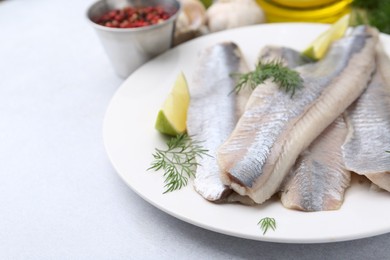 Photo of Marinated herring fillets with lime and dill on grey table, closeup. Space for text