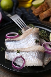 Photo of Marinated herring fillets with onion rings and thyme on table, closeup