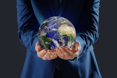 Image of Planet in our hands. Man holding Earth model on dark grey background, closeup