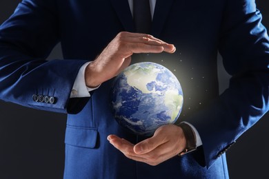 Image of Planet in our hands. Man holding glowing Earth on dark grey background, closeup