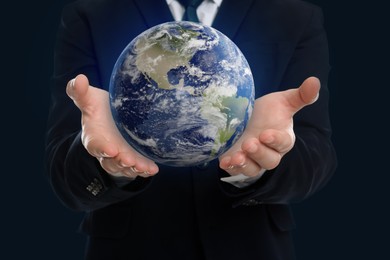 Image of Planet in our hands. Man holding Earth model on dark blue background, closeup