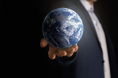 Image of Planet in our hands. Man holding Earth model on black background, closeup