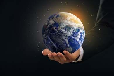 Image of Planet in our hands. Man holding glowing Earth on dark background, closeup