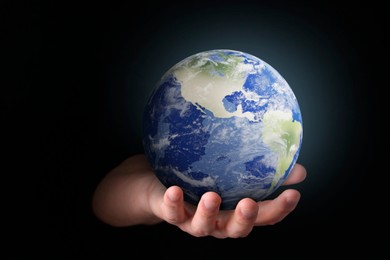 Image of Planet in our hands. Man holding Earth model on black background, closeup