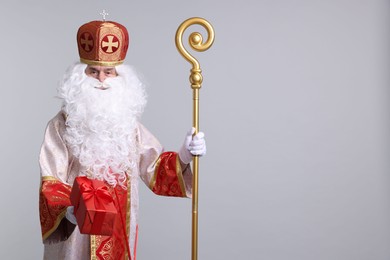 Photo of Saint Nicholas with gift on light grey background. Space for text