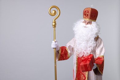 Photo of Saint Nicholas with gift on light grey background. Space for text