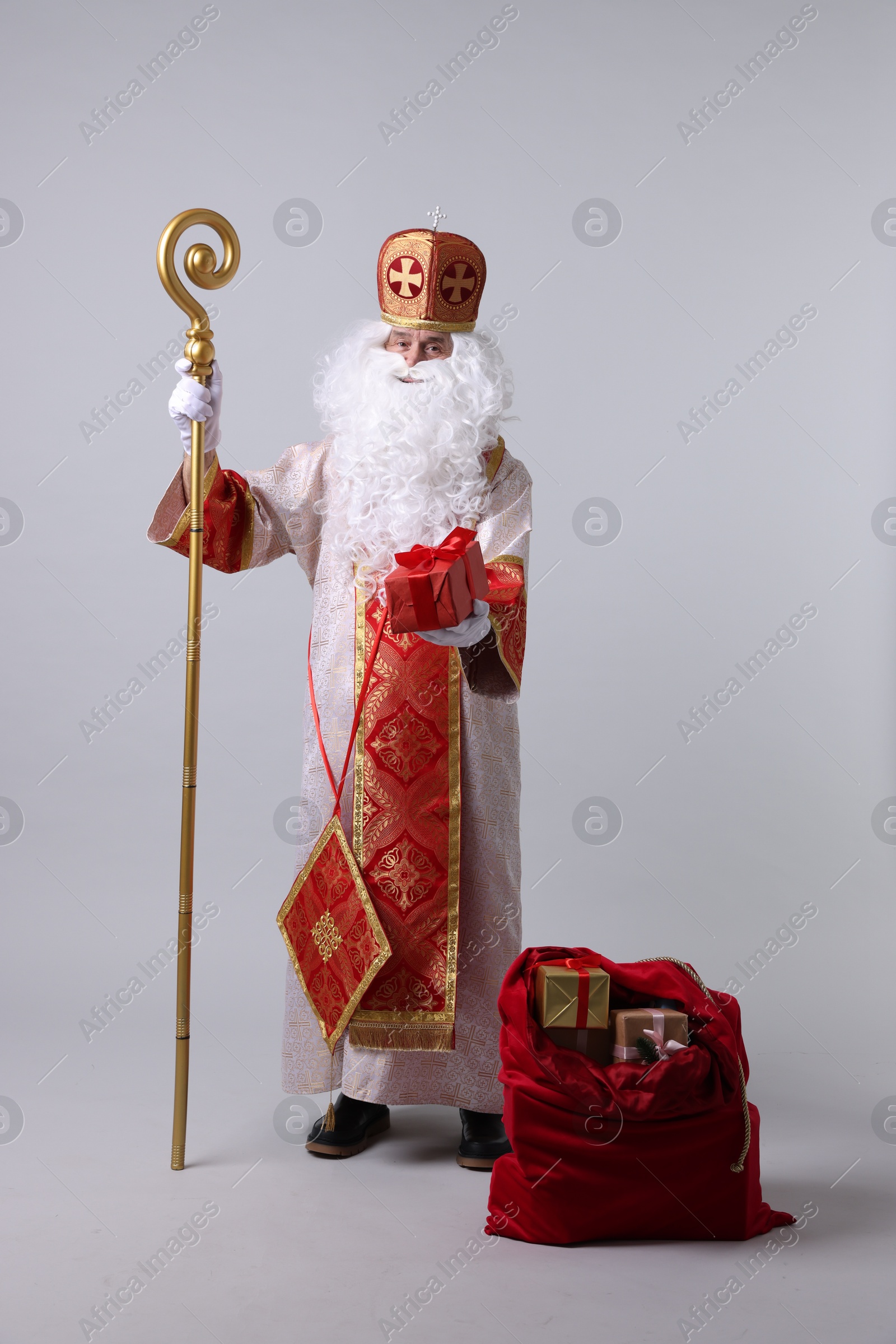 Photo of Saint Nicholas with sack full of gifts on light grey background