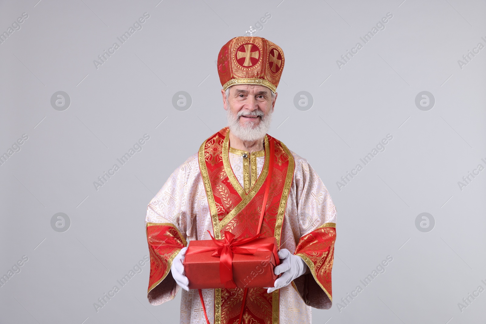 Photo of Saint Nicholas with gift on light grey background