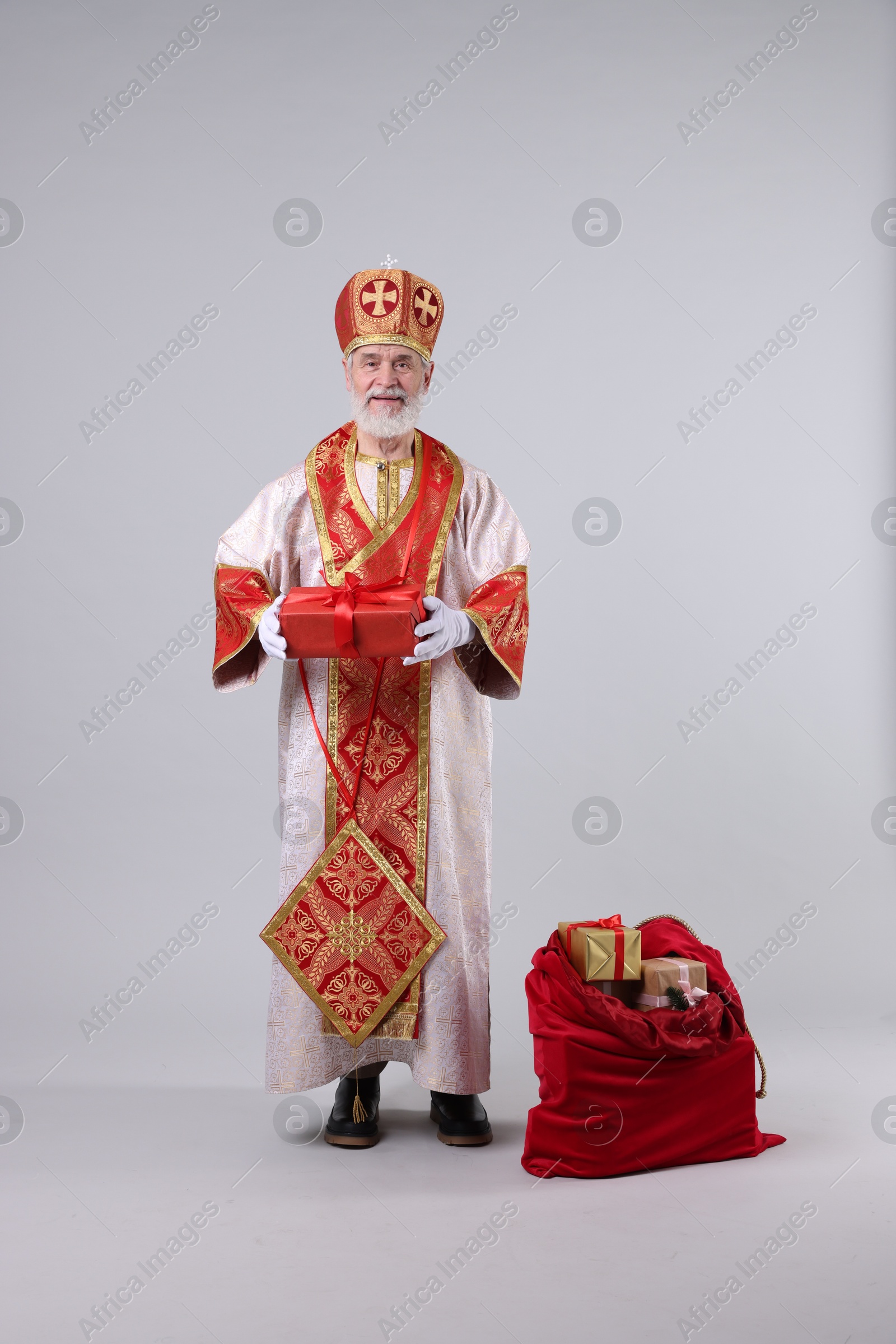 Photo of Saint Nicholas with sack full of gifts on light grey background