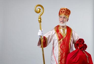 Photo of Saint Nicholas with sack on light grey background. Space for text