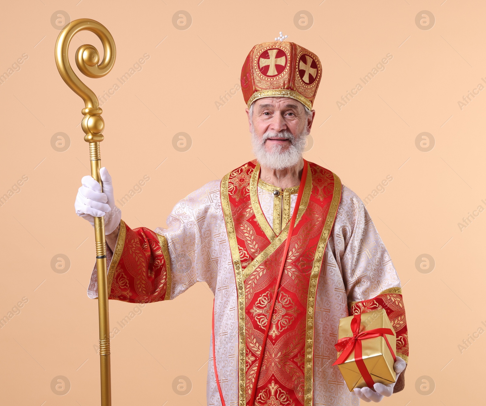 Photo of Saint Nicholas with gift on beige background