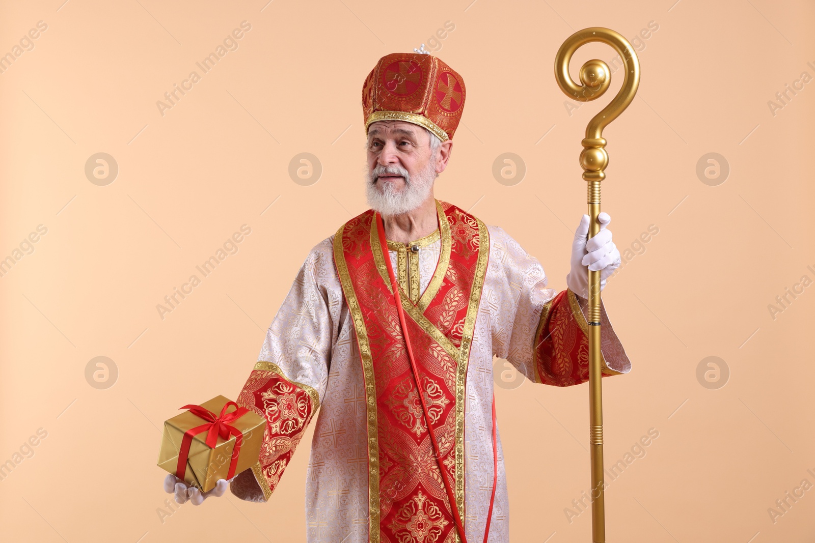 Photo of Saint Nicholas with gift on beige background