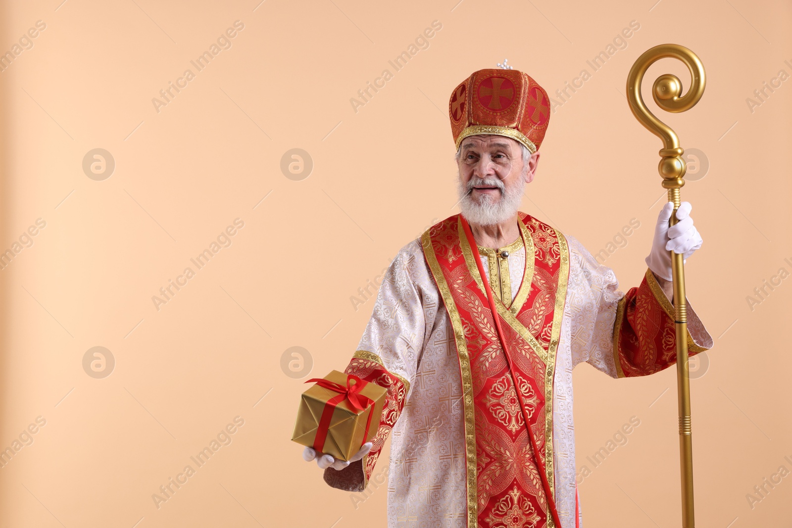 Photo of Saint Nicholas with gift on beige background. Space for text