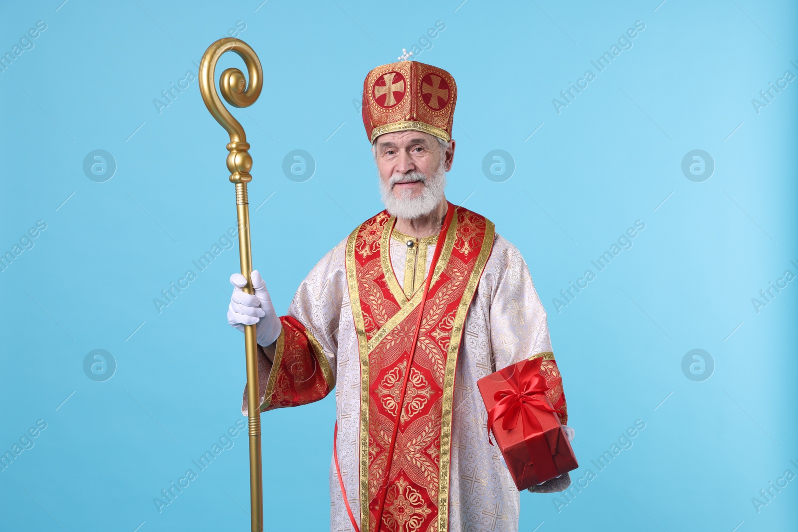 Photo of Saint Nicholas with gift on light blue background