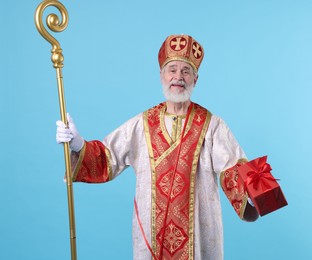 Photo of Saint Nicholas with gift on light blue background