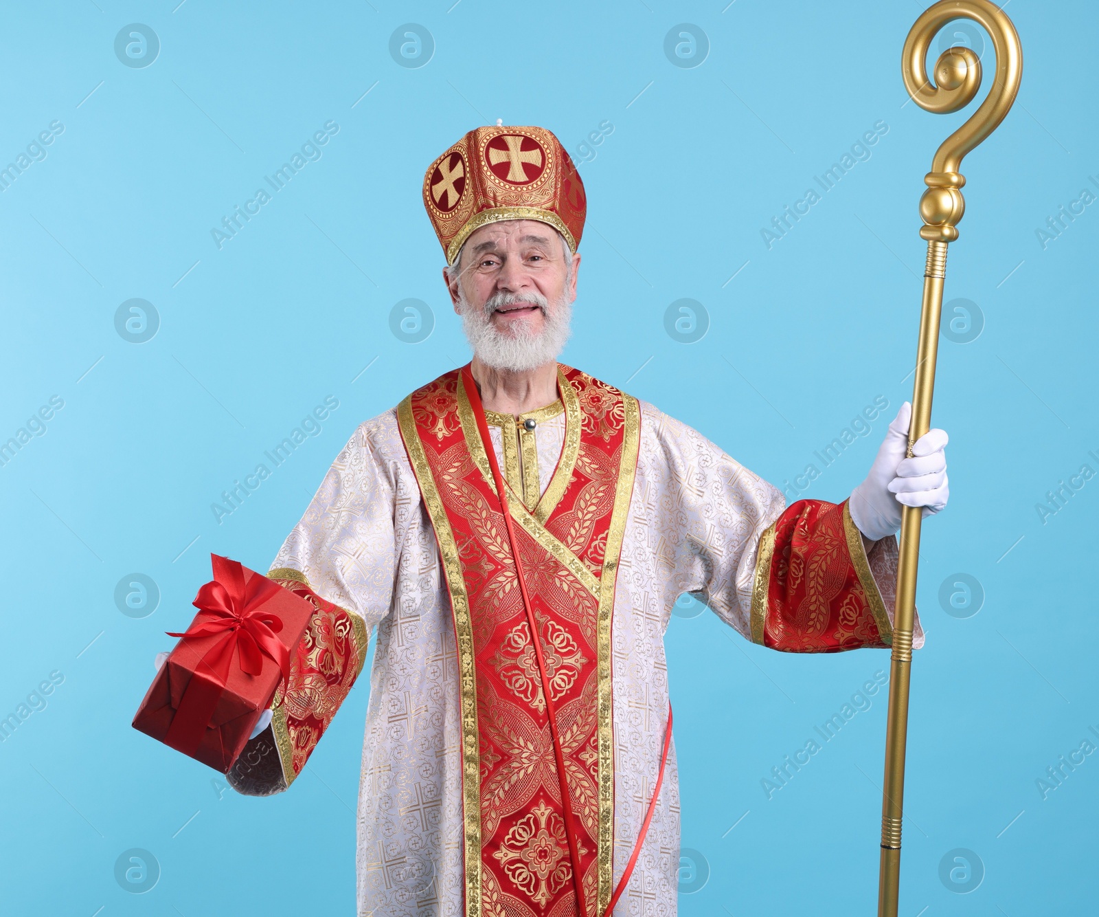 Photo of Saint Nicholas with gift on light blue background