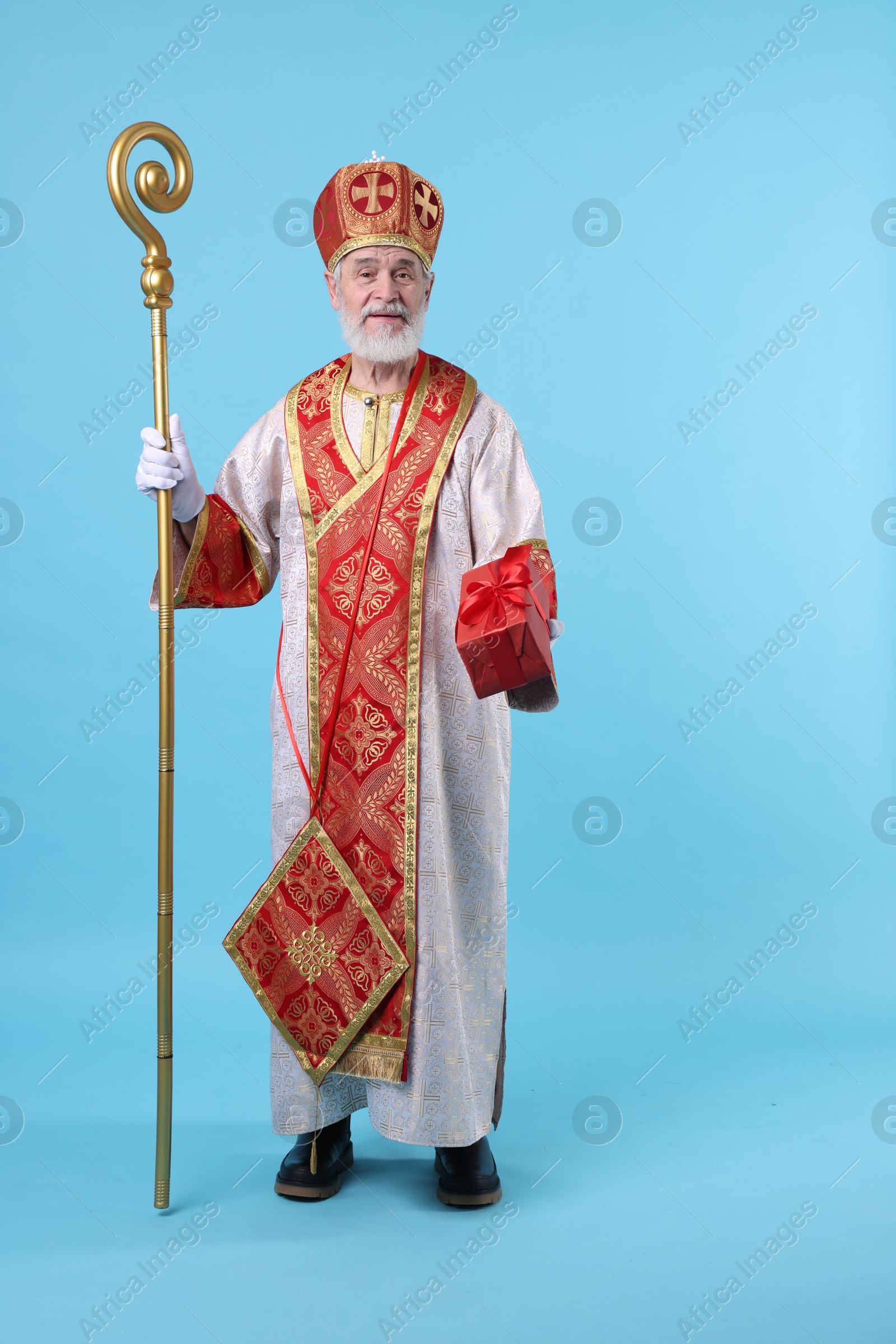 Photo of Saint Nicholas with gift on light blue background