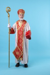 Photo of Saint Nicholas with gift on light blue background