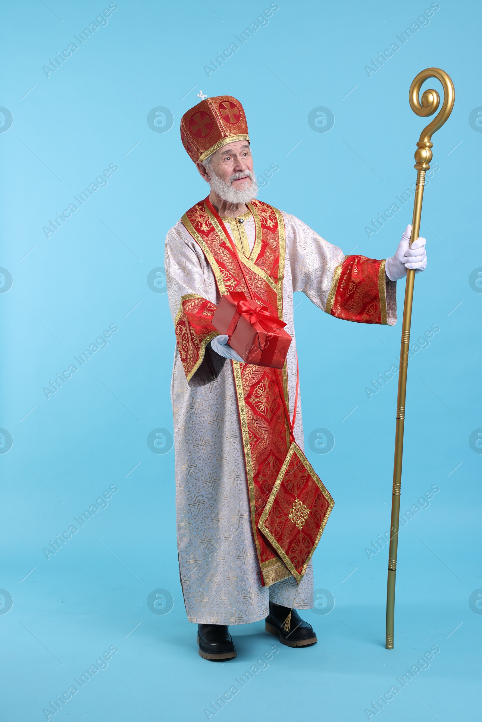 Photo of Saint Nicholas with gift on light blue background