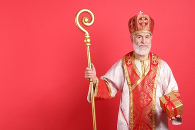 Photo of Saint Nicholas with gift on red background. Space for text