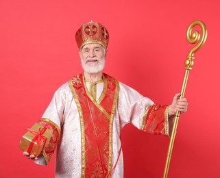 Photo of Saint Nicholas with gift on red background