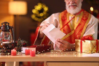 Saint Nicholas with letter at desk in room decorated for Christmas, closeup