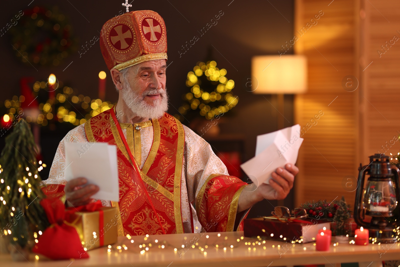 Photo of Saint Nicholas with letters at desk in room decorated for Christmas